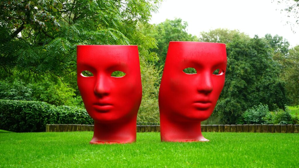 red human face monument on green grass field